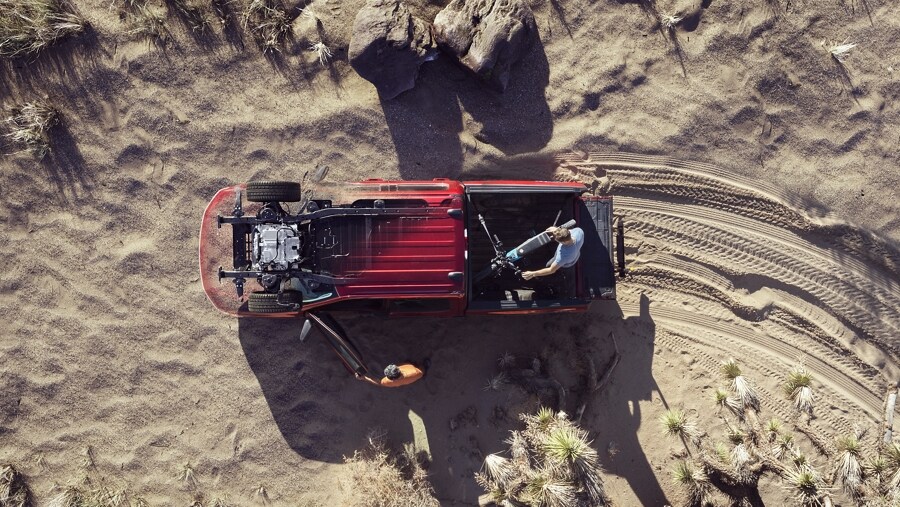 Overhead shot of people unloading a motorcycle from the bed of the 2023 Ford F-150® Lightning®