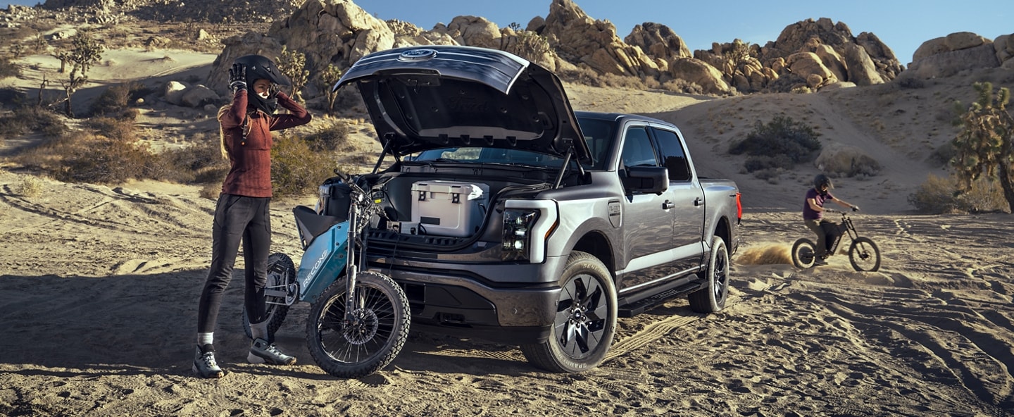 Cyclist in the desert unloading gear from the frunk of a 2023 Ford F-150® Lightning®