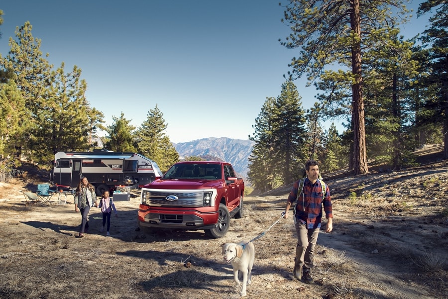 2023 Ford F-150® Lightning® parked at mountainous campsite with family going on hike with a dog