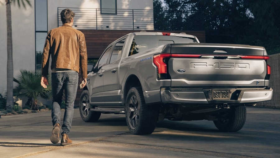 Man walking toward the 2023 Ford F-150® Lightning®, showing the rear tailgate