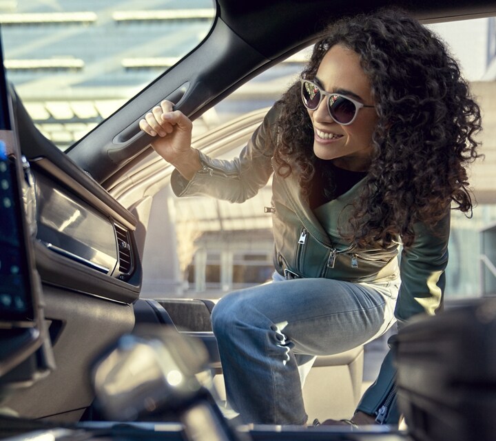 Woman getting into the passenger side of a 2023 Ford F-150® Lightning® using the interior handle