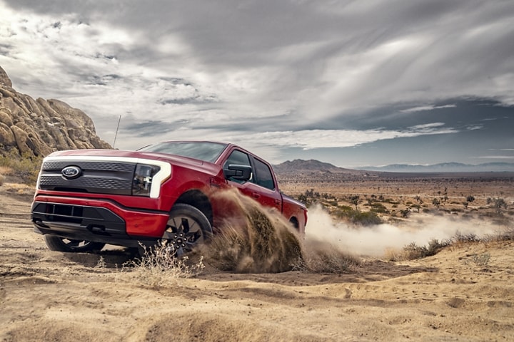 A 2023 Ford F-150® Lightning® being driven on sandy terrain