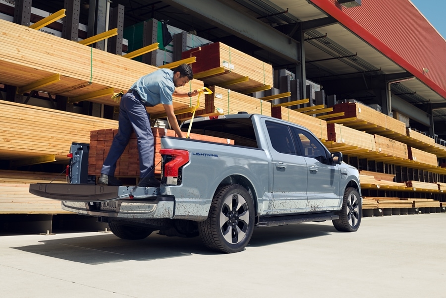 A 2023 Ford F-150® Lightning® in a lumber yard being loaded with a heavy pallet of boards