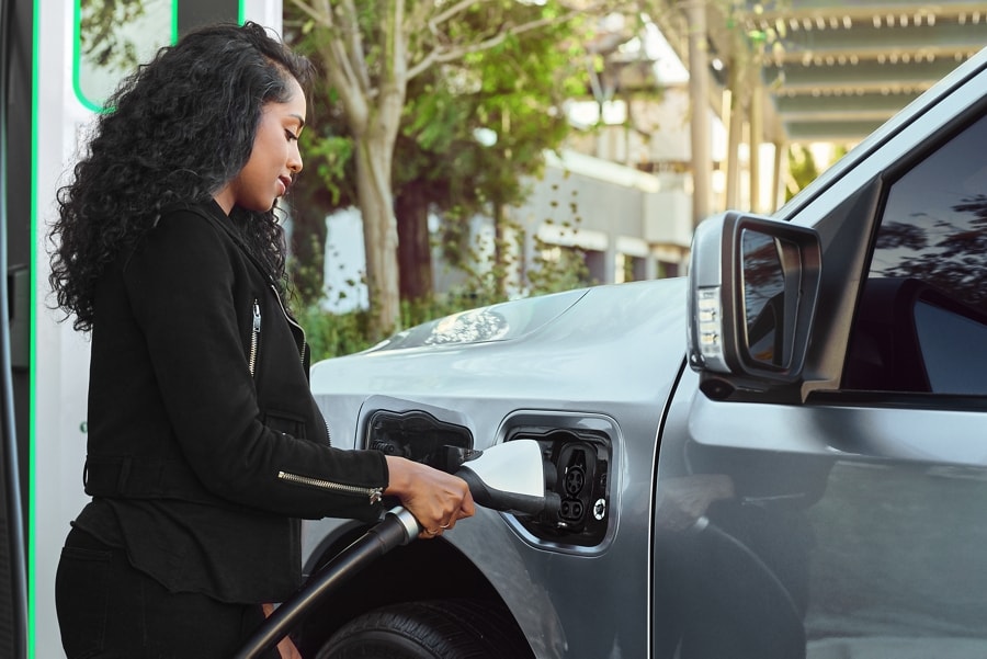 Woman plugging in her 2023 Ford F-150® Lightning® at a public charging station