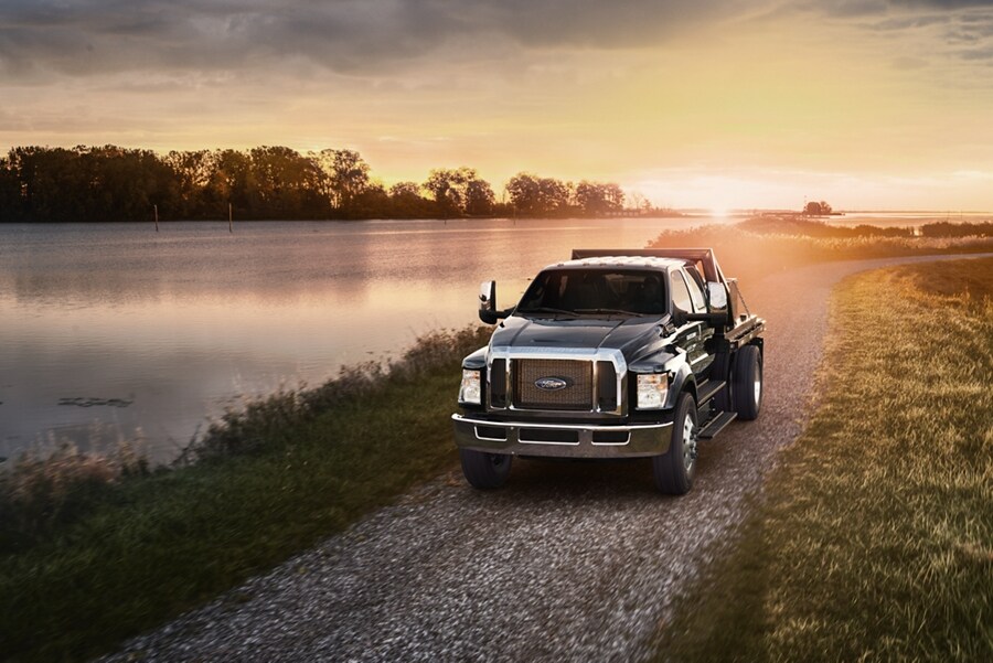 2023 Ford F-750 Crew Cab in Agate Black with utility stake bed upfit being driven near a lake