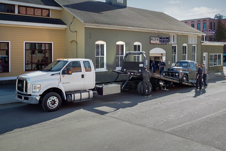 2023 Ford F-650 SuperCab with rollback body flatbed with tow truck upfit in Oxford White towing vehicle