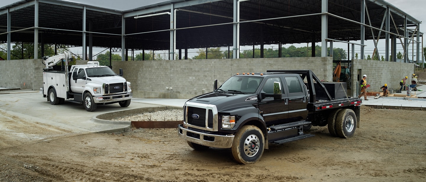 2023 Ford F-750 SuperCab with upfit in Oxford White and 2023 Ford F-750 Crew Cab in Agate Black with upfit at worksite