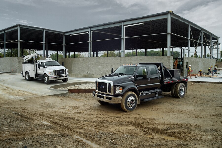 2023 Ford F-750 SuperCab with upfit in Oxford White and 2023 Ford F-750 Crew Cab in Agate Black with upfit at worksite