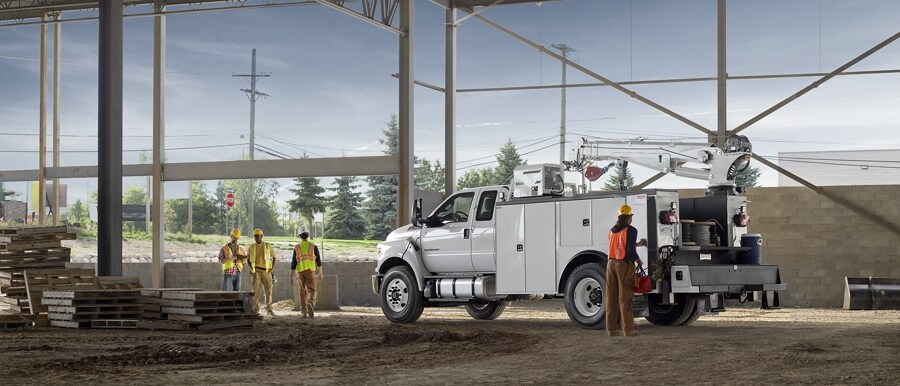 Workers near 2023 Ford F-750 SuperCab in Oxford White with mechanic truck upfit parked at construction site