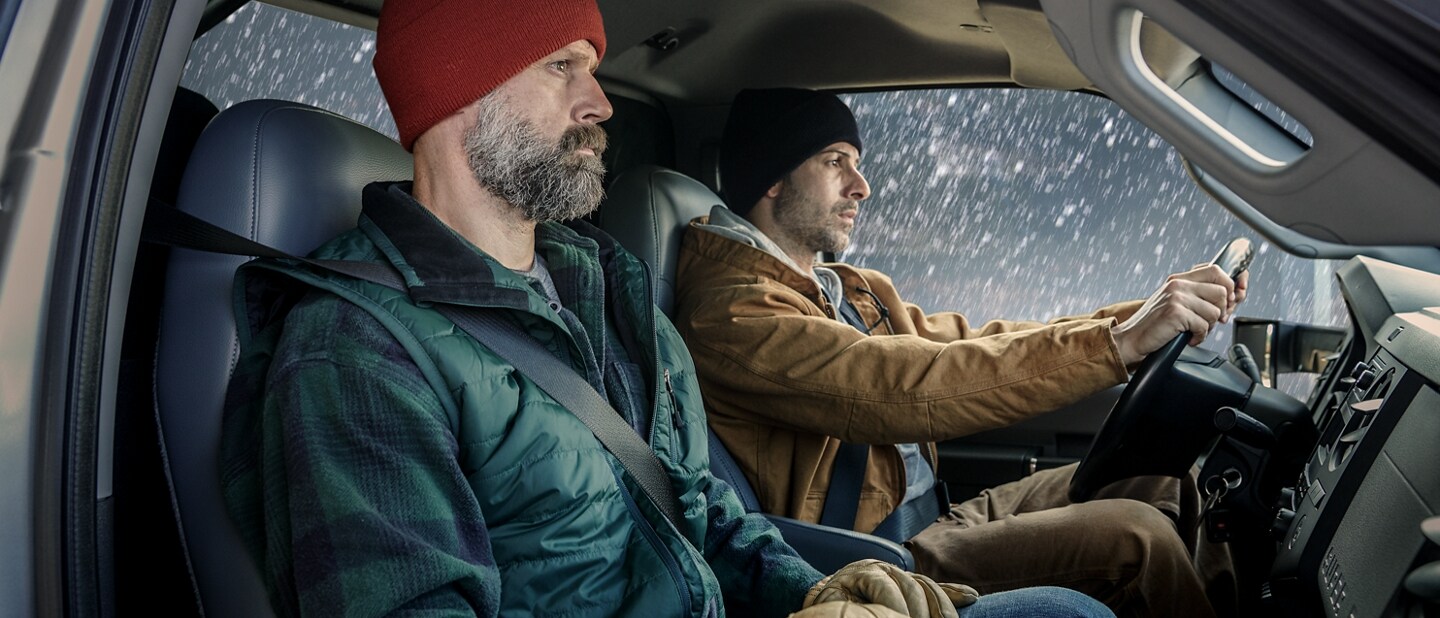 Two men sitting in the front cab and snowing outside