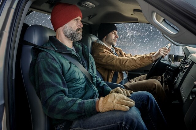 Two men sitting in the front cab and snowing outside