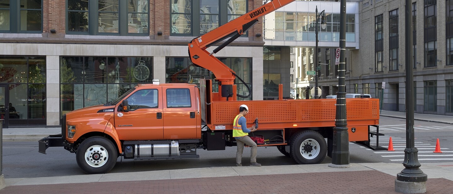 Workers changing city streetlight using 2023 Ford F-750 Crew Cab in Tangier Orange with aerial lift upfit