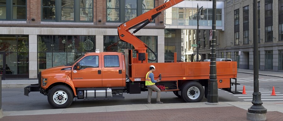 Workers changing city streetlights using 2023 F-750 Crew Cab with aerial lift upfit in Tangier Orange