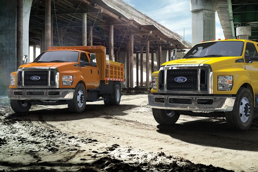 2023 Ford F-750 models with dump truck upfits parked alongside one another near overpass