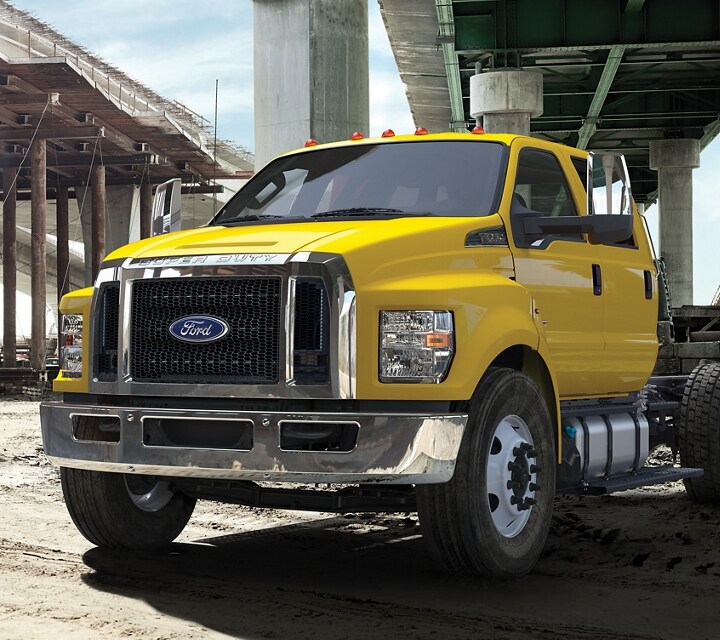 2023 Ford F-750 models with dump truck upfits parked alongside one another near overpass