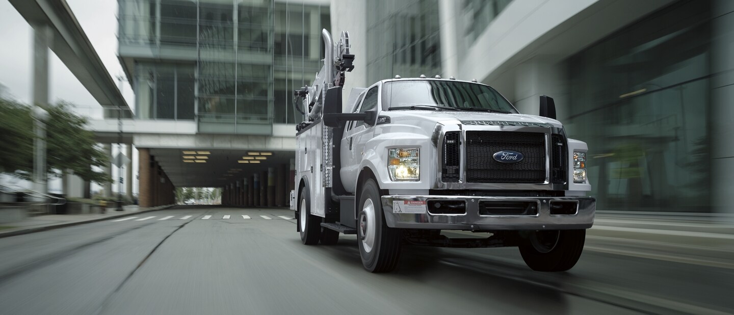 2023 Ford F-750 SuperCab in Oxford White with mechanic truck upfit being driven near large building