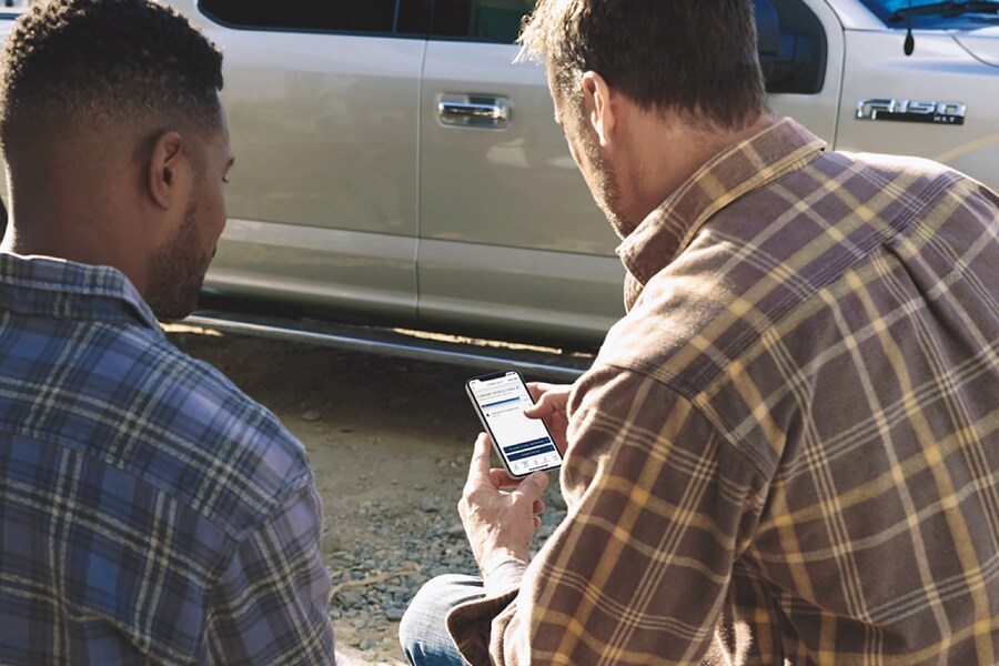 Two men looking at a smartphone that features the Telematics Drive app