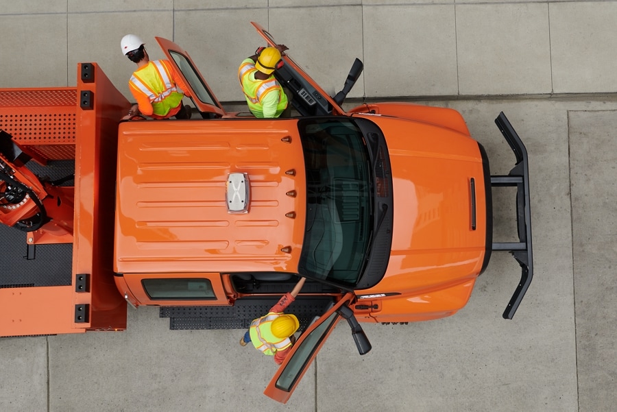 Aerial view of workers exiting 2024 Ford F-750 Crew Cab with aerial lift upfit in Tangier Orange