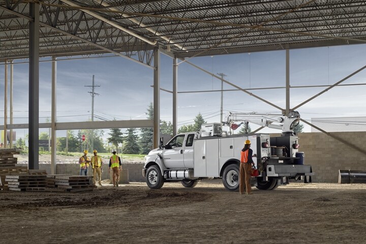 Workers near 2024 Ford F-750 SuperCab with mechanic truck upfit in Oxford White parked at construction site