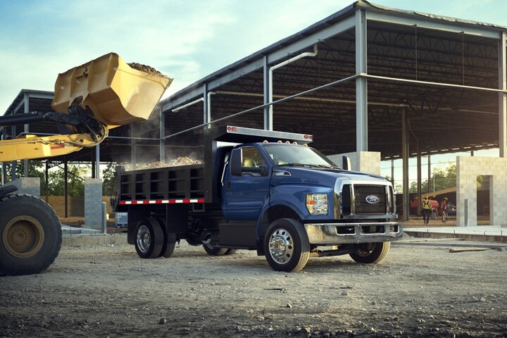 Front end loader dumping dirt into dump truck upfit of 2024 Ford F-750 Regular Cab in Blue Jeans