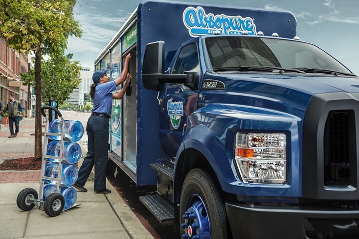 Close-up of a worker unloading water from 2024 Ford F-750 Regular Cab in Blue Jeans with beverage truck upfit