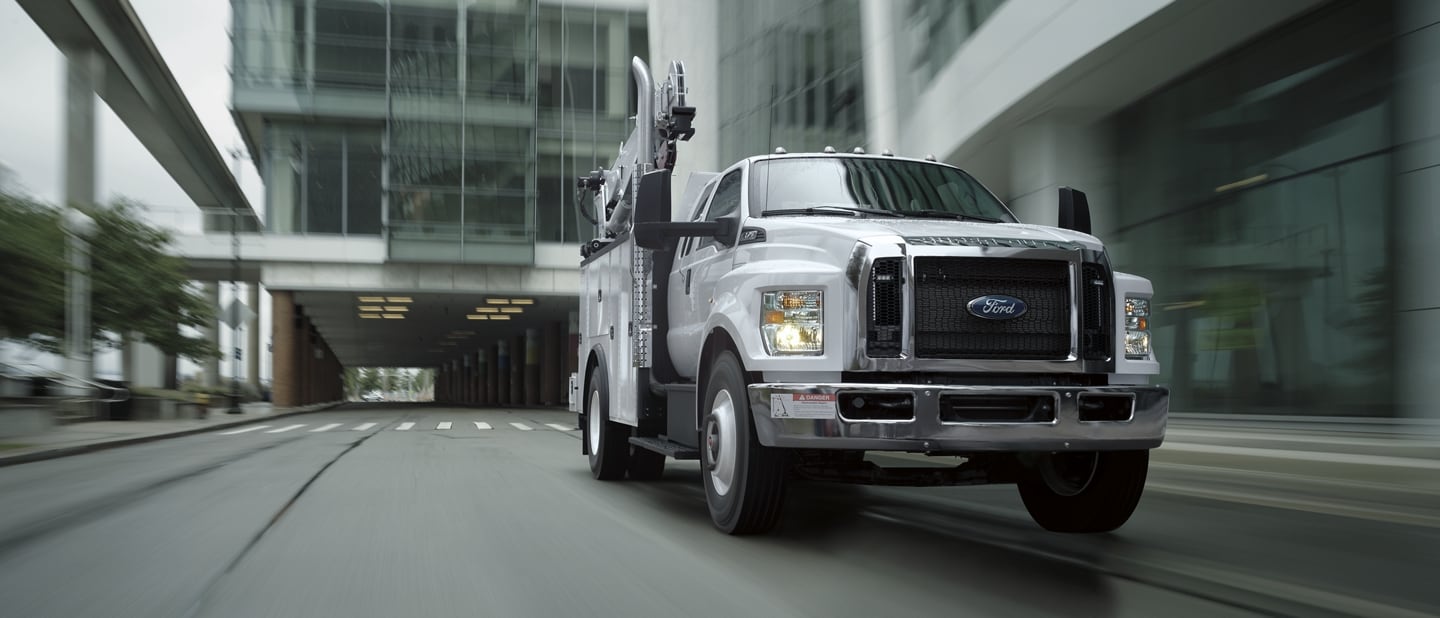 2024 Ford F-750 SuperCab in Oxford White with mechanic truck upfit being driven near large building