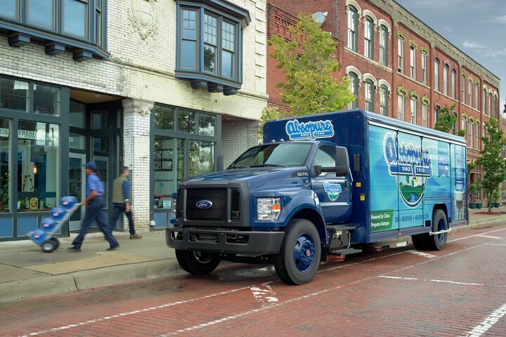 Worker unloading water from 2024 Ford F-750 Regular Cab with beverage truck upfit and Absopure custom design