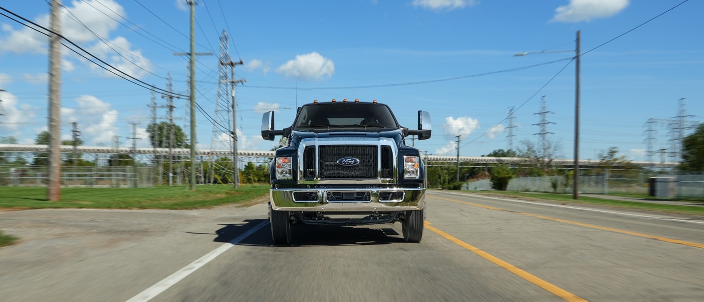 2025 Ford F-750 Crew Cab in Agate Black being driven on road near telephone lines