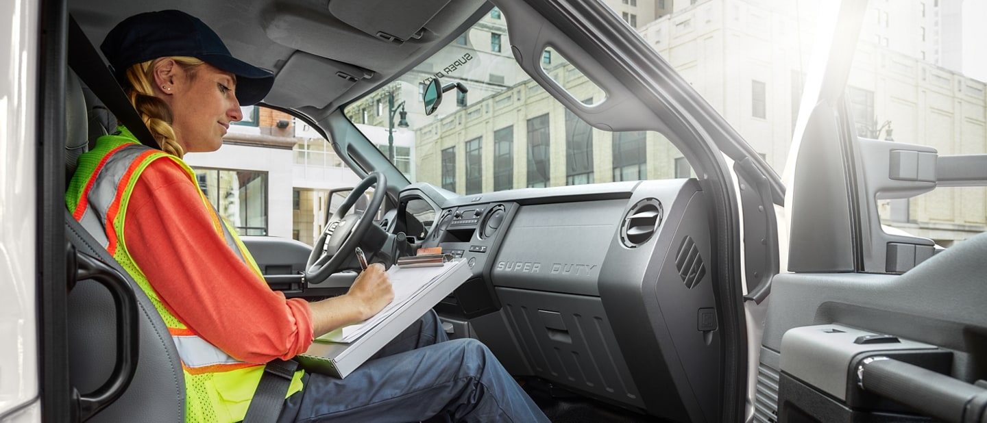 Worker writing on clipboard in passenger seat of 2025 Ford F-750 Crew Cab in Oxford White