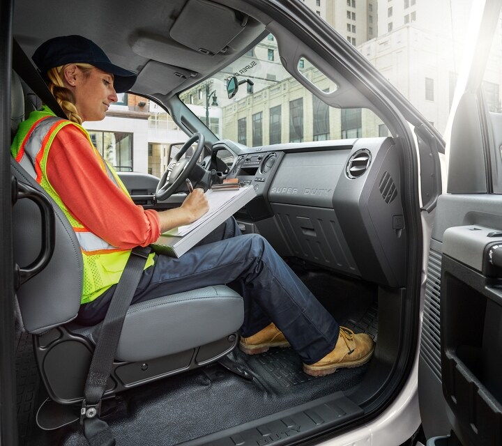 Worker writing on clipboard in passenger seat of 2025 Ford F-750® Crew Cab in Oxford White