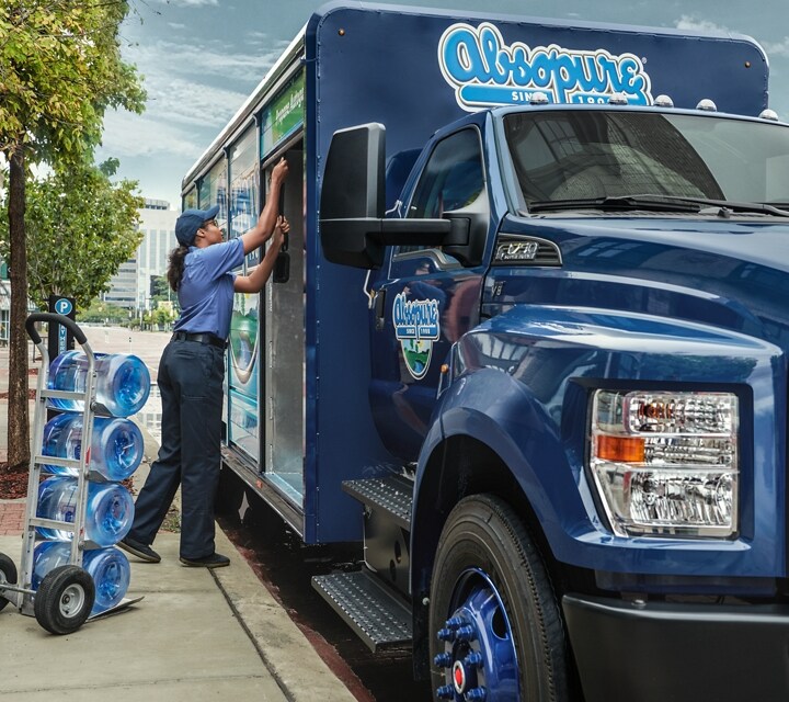 Close-up on worker unloading water from 2026 Ford F-750® Regular Cab in custom design with beverage truck upfit on city street