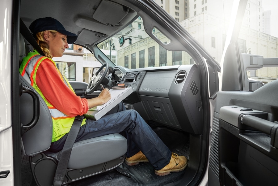 Worker writing on clipboard in passenger seat of 2026 Ford F-750® Crew Cab in Oxford White