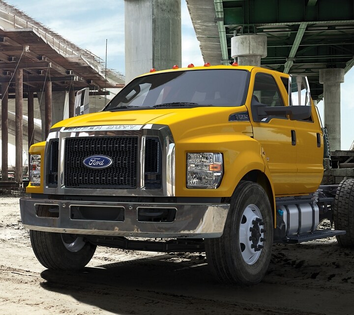 2026 Ford F-750® models with dump truck upfits parked alongside one another near an overpass
