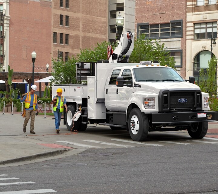 Workers walking near 2026 Ford F-750® Crew Cab in Oxford White with aerial lift upfit