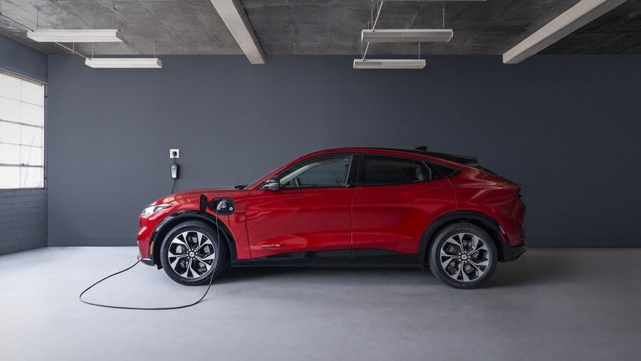 Side view of the 2023 Ford Mustang Mach-E® plugged into a home charger in a garage
