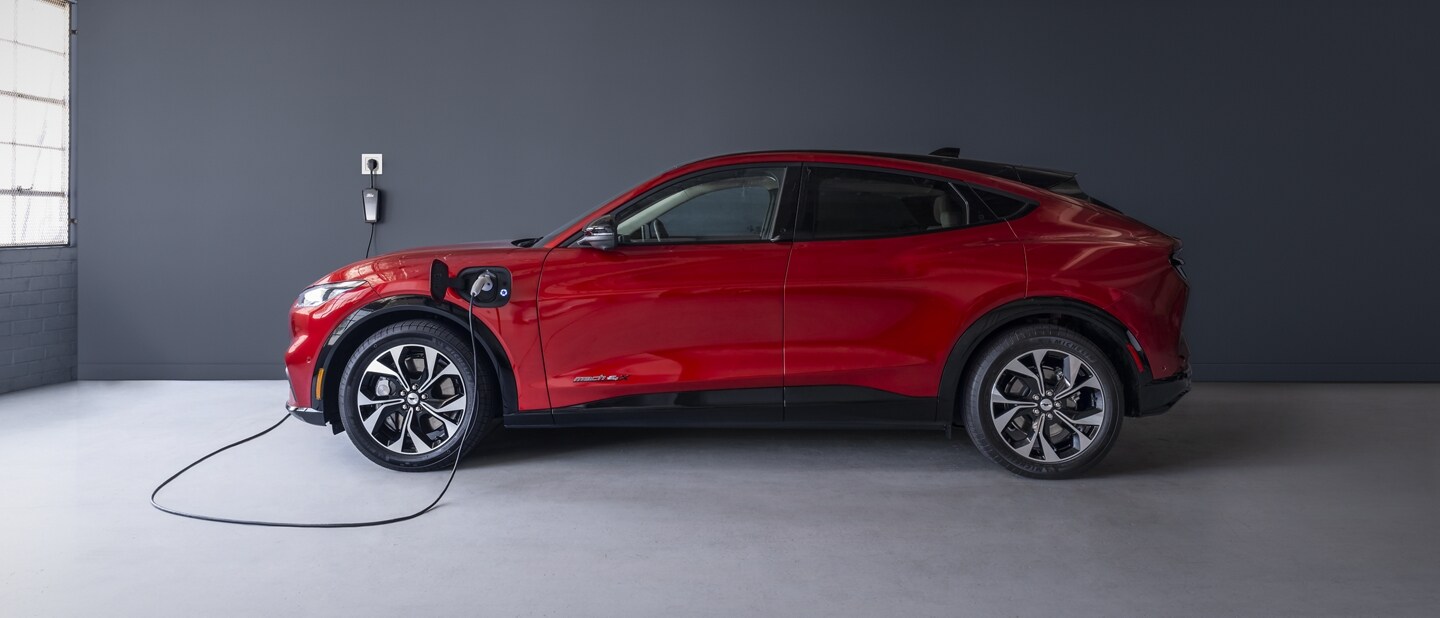 Side view of the 2023 Ford Mustang Mach-E® plugged into a home charger in a garage