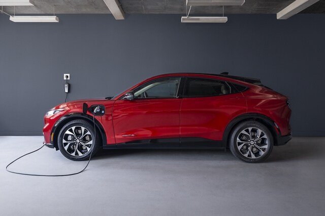 Side view of the 2023 Ford Mustang Mach-E® plugged into a home charger in a garage