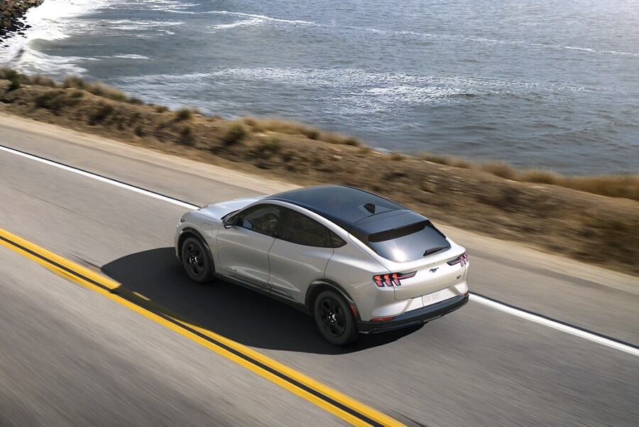 Overhead view of a 2023 Ford Mustang Mach-E® California Route 1 on a highway next to the ocean