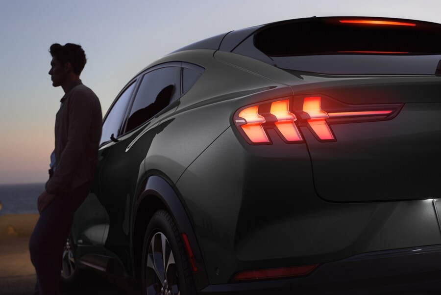 Man leaning against the side of a 2023 Ford Mustang Mach-E® at dusk