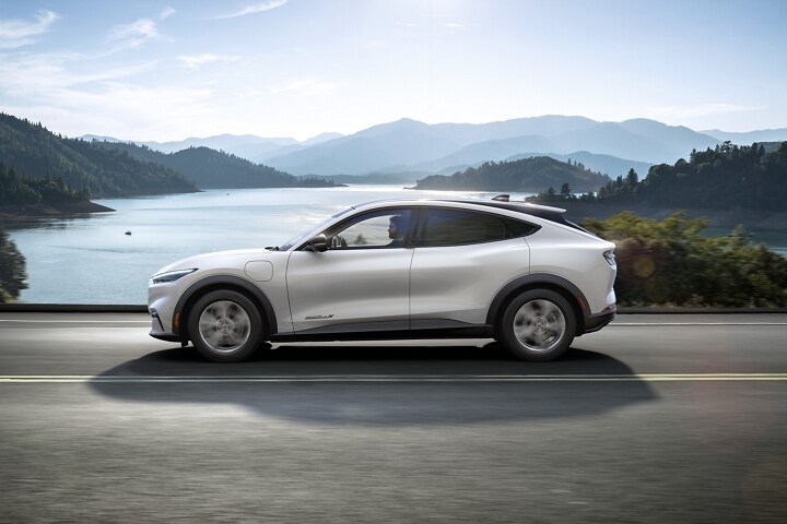 2023 Ford Mustang Mach-E® driving on a highway next to mountains and a lake