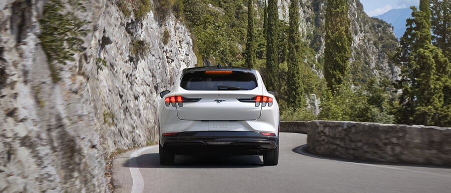 Rear view of a 2023 Ford Mustang Mach-E® being driven on a scenic mountain highway