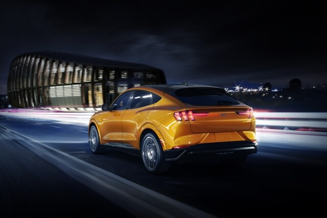 A 2023 Ford Mustang Mach-E® GT being driven at night near a stadium