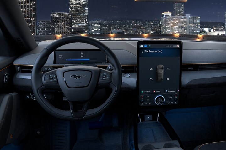 Interior view of 2023 Ford Mustang Mach-E® at night with city skyline visible through the windshield