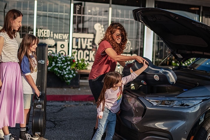 Woman helps child put a musical instrument into the frunk of a 2023 Mustang Mach-E® SUV