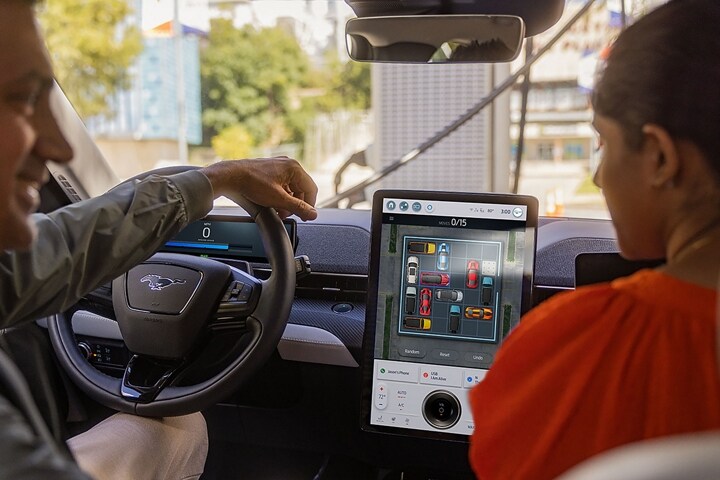 Two people inside a parked 2023 Ford Mustang Mach-E® SUV with a game on the portrait touchscreen