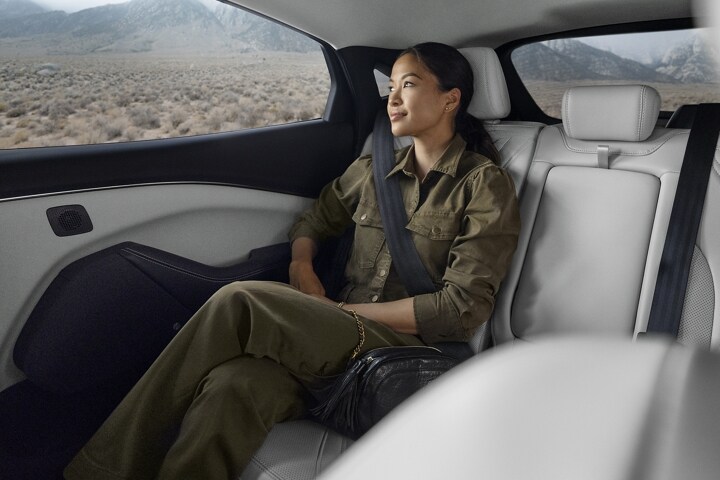 Woman sitting comfortably in the roomy backseat of a 2023 Ford Mustang Mach-E® SUV