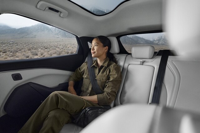 Woman sitting in the spacious back seat of a 2023 Ford Mustang Mach-E® with plenty of legroom