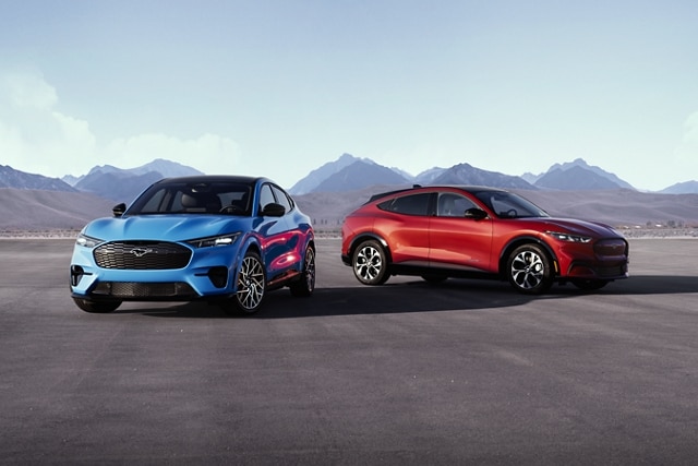 Two 2023 Ford Mustang Mach-E® SUVs shown in Rapid Red and Grabber Blue parked with mountains in the background