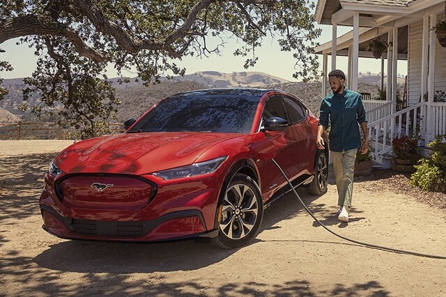 A 2023 Ford Mustang Mach-E® Premium plugged in outside a farmhouse