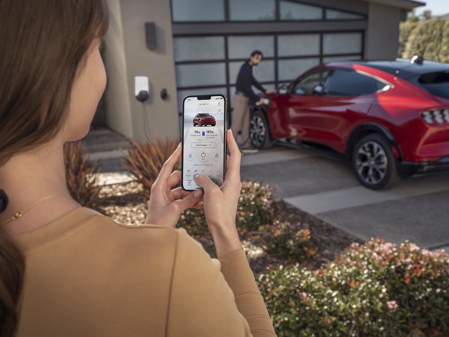 A woman is holding her smartphone and unlocking the vehicle using the Ford Pass App